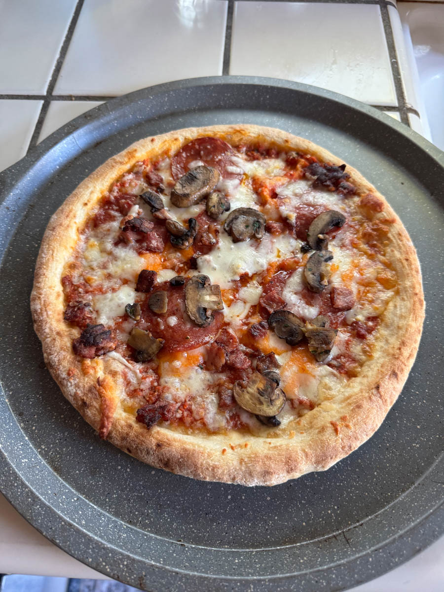 cooked sopressata bacon and mushroom pizza on the table