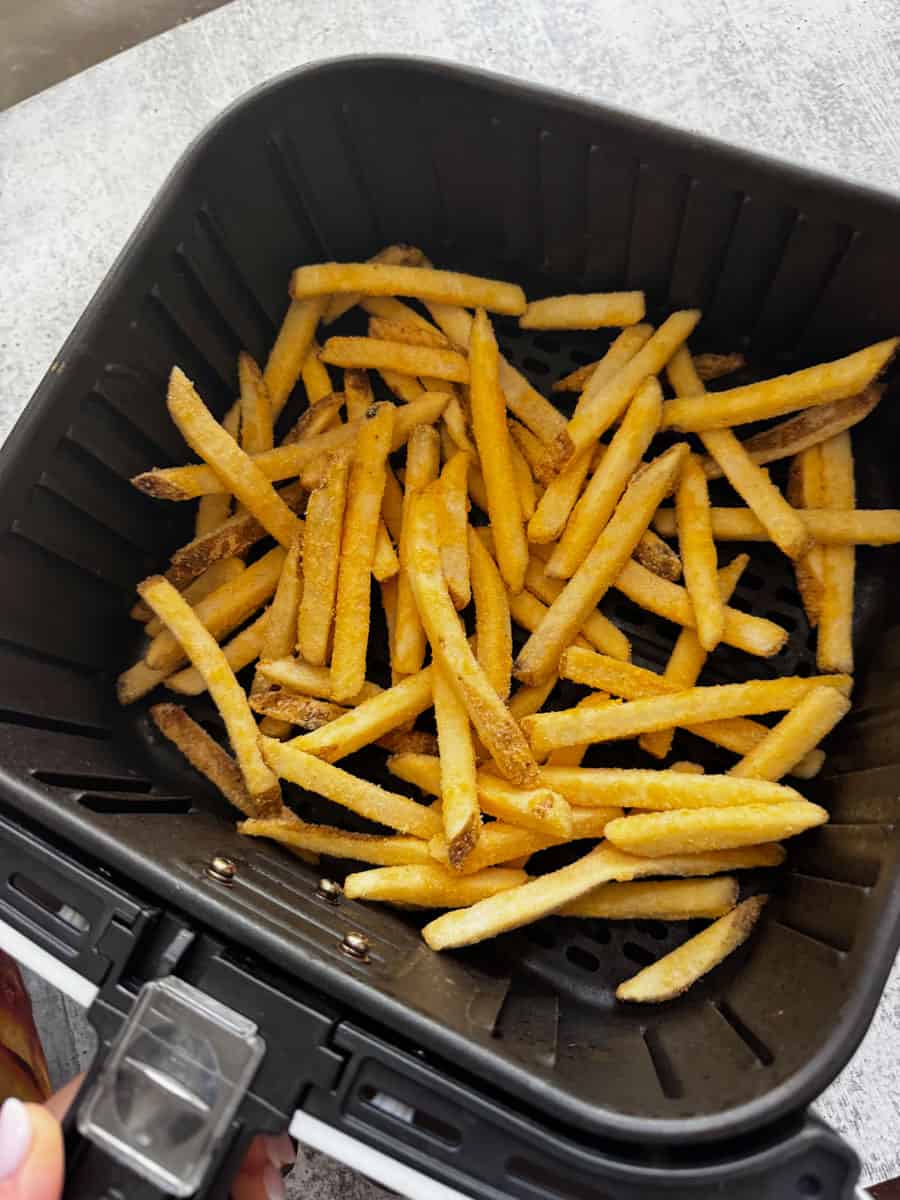 French fries cooking in an air fryer basket, ready to be served.
