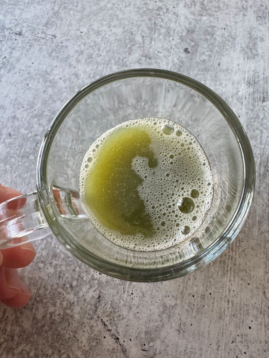 Green juice in a clear glass mug with foam, healthy drink from Costco finds.