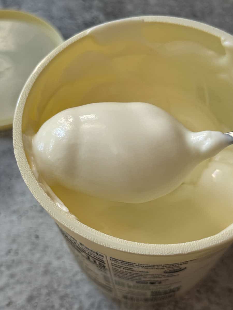 Close-up of creamy, smooth yogurt in a Costco container with a spoon.