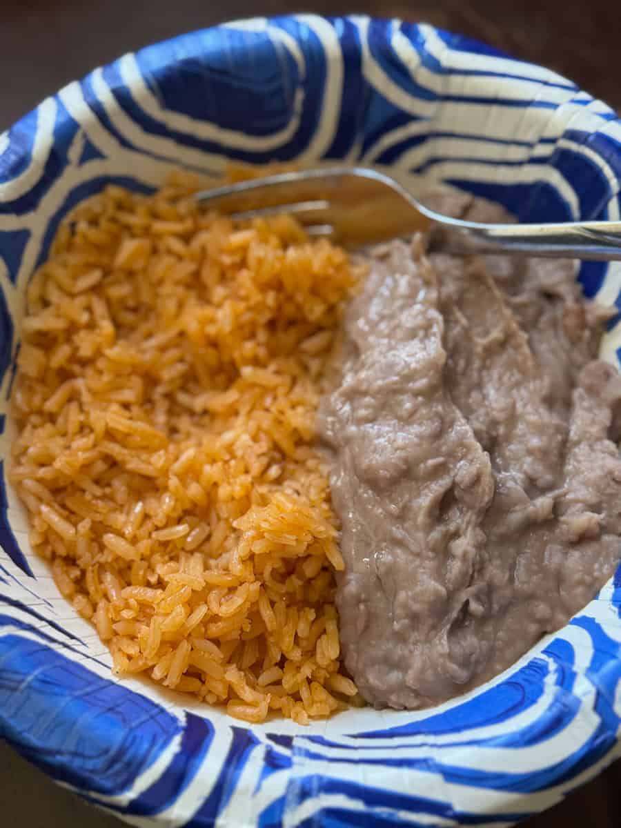Close-up of rice and beef stew in a blue and white bowl with a spoon.
