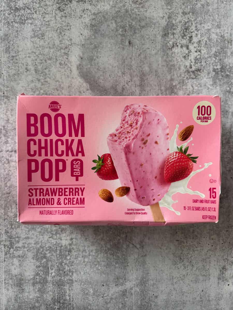 Strawberry almond and cream ice cream bar with pink coating and fresh strawberries.