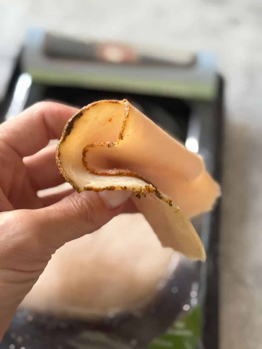 Hand holding a cheese roll with a crispy crust, ready to eat, at Costco.