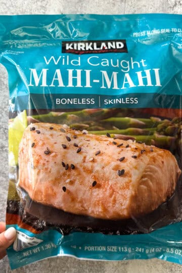 Fresh wild caught mahi-mahi fish fillet in packaging with black sesame seeds.