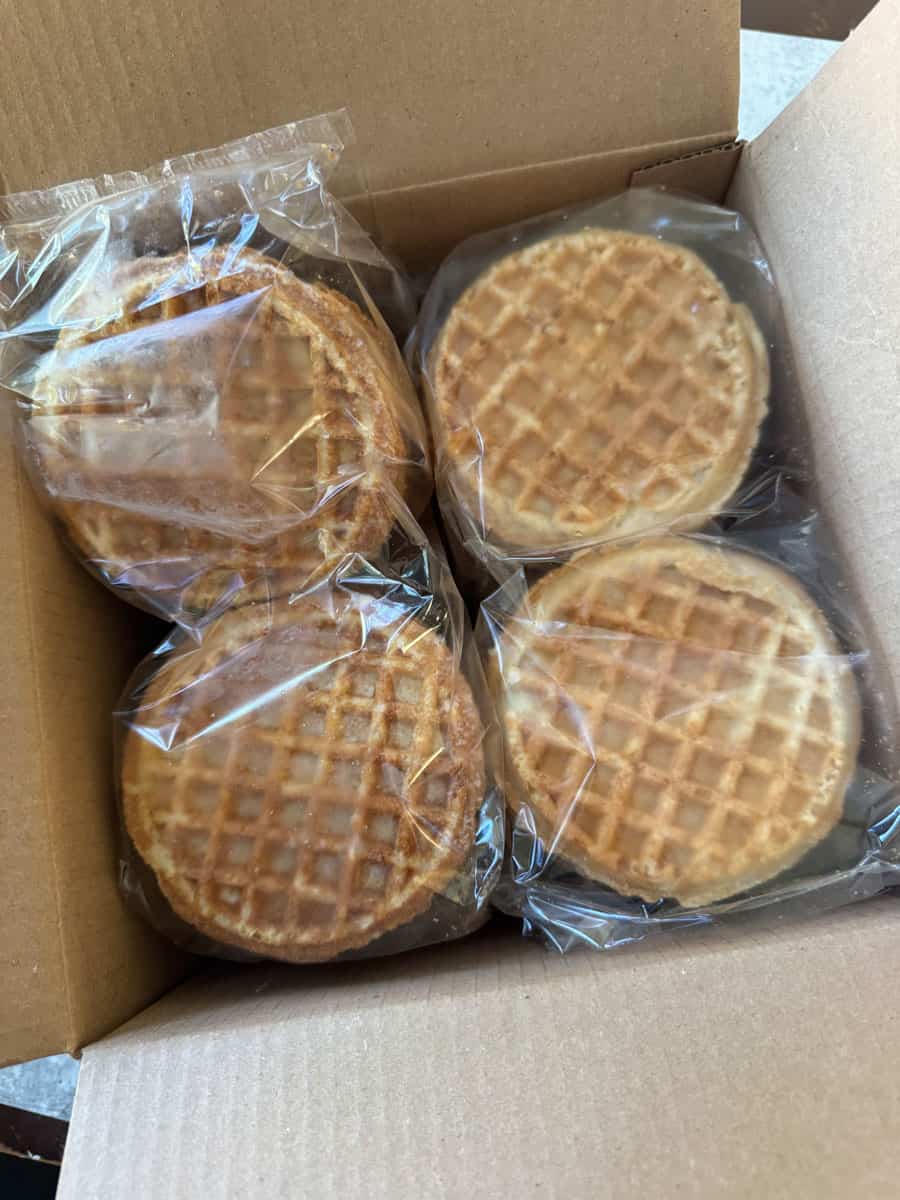 Four packaged waffles in a cardboard box, ready for sale or storage.