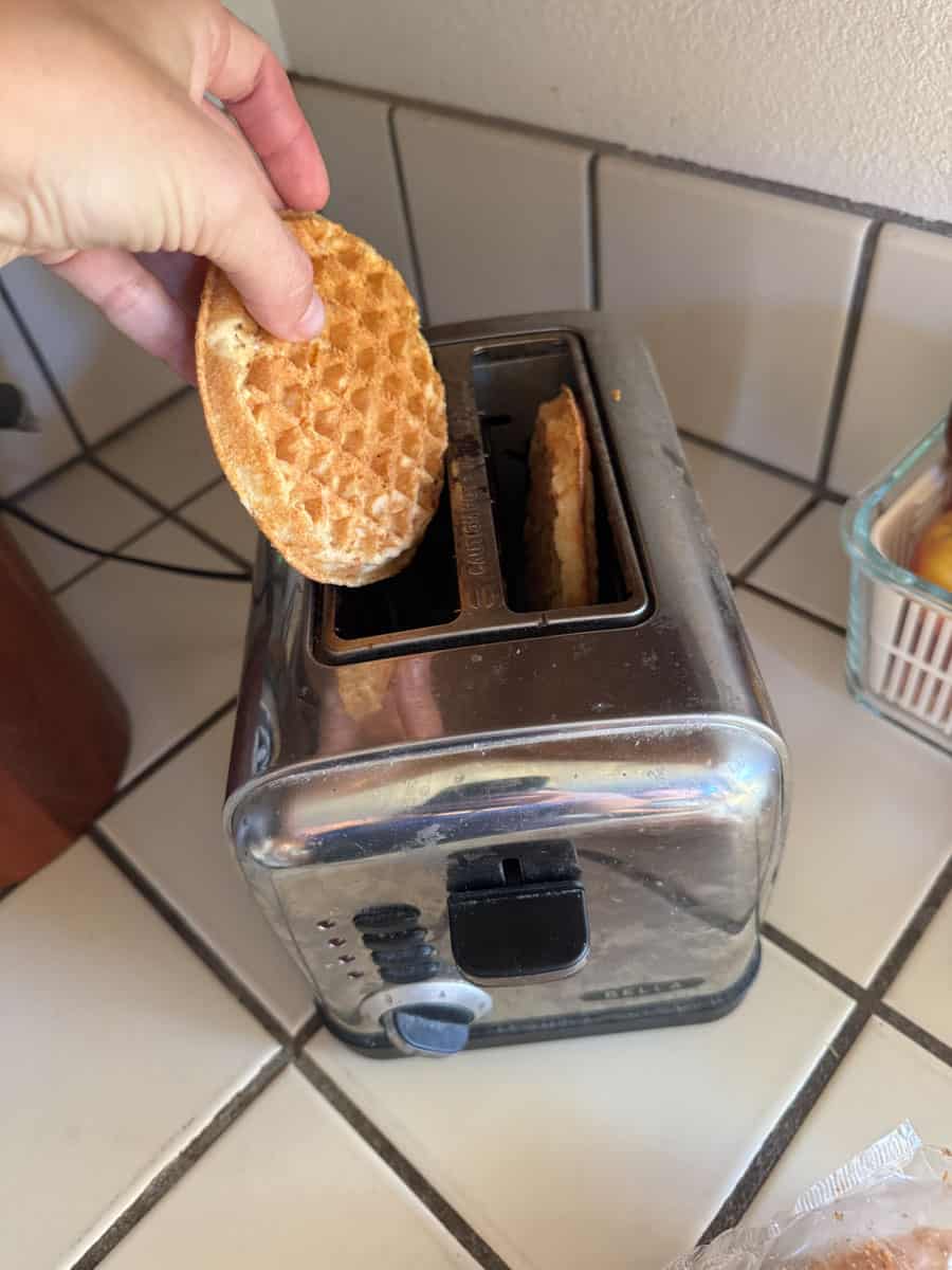 Hand placing waffle into toaster for breakfast at Costco.