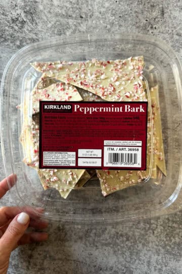 Kirkland Peppermint Bark in clear plastic container with festive sprinkles.