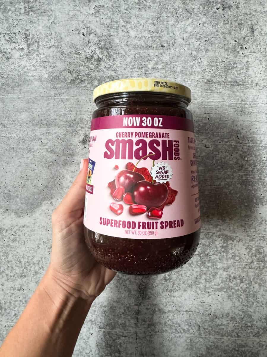 Costco cherry pomegranate superfood fruit spread jar held in hand.