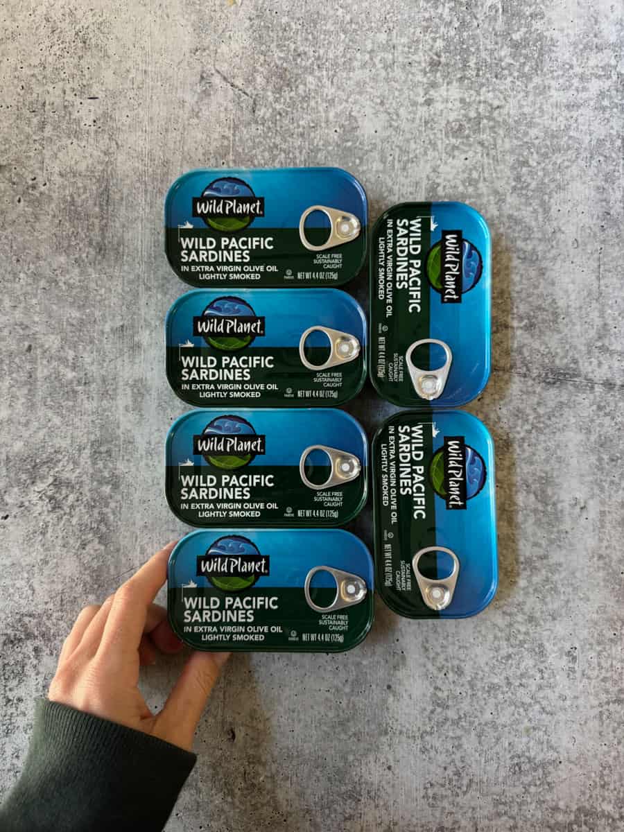 C discounted Wild Planet sardines in blue can stack on gray surface.