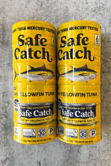 Two cans of Safe Catch yellowfin tuna on a textured surface.