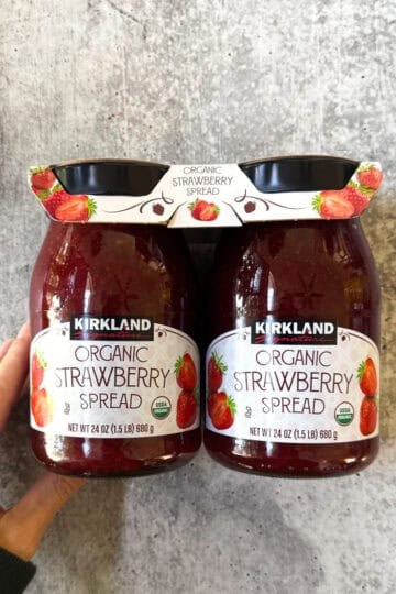 Kirkland organic strawberry spread jars with hand for scale.